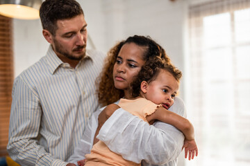 African American mother tosses young baby girl up in living room at home. 