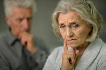 Close up portrait of sad senior couple posing at home