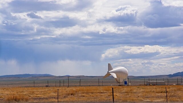 Aerostat tethered near ground with spring storm approaching  to south
