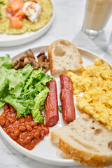 Simple American style Breakfast with sausages, scrambled eggs, baked beans, mushrooms and tomatoes. This dish is full of nutrients that you needed.