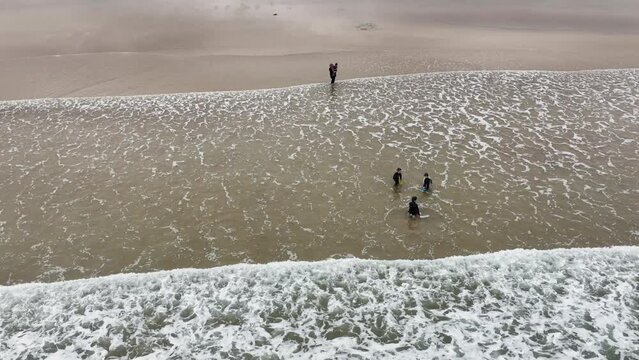Aerial video of a family having fun on the Beautiful Tullagh Strands Sandy Beach on the Atlantic Ocean in County Donegal Ireland 08-08-23