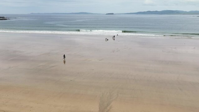 Aerial video of a family having fun on the Beautiful Tullagh Strands Sandy Beach on the Atlantic Ocean in County Donegal Ireland 08-08-23