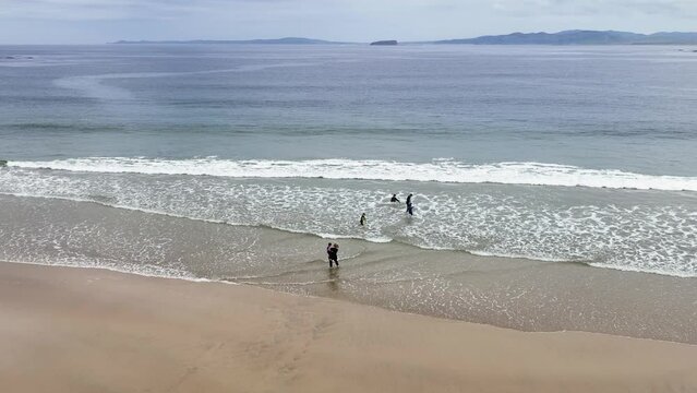 Aerial video of a family having fun on the Beautiful Tullagh Strands Sandy Beach on the Atlantic Ocean in County Donegal Ireland 08-08-23