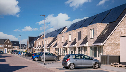 Newly build houses with solar panels attached on the roof against a sunny sky. black solar panels on a roof