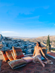 Young woman in dress on the roof with amazing view of Cappadocia in Turkey