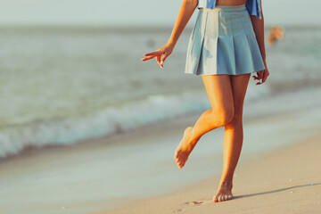 Teen girl's legs on the beach closeup. Girl walking on the beach