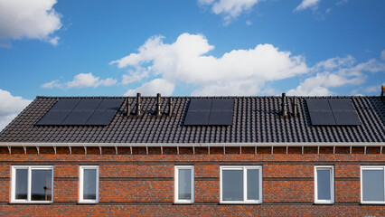 Newly build houses with solar panels attached on the roof Close up of new building with black solar...