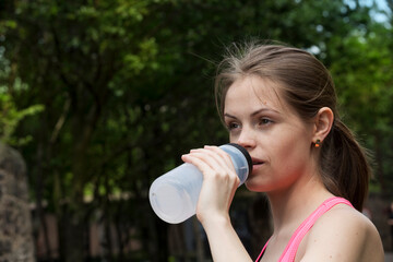 Athletic woman drinking water outdoors.