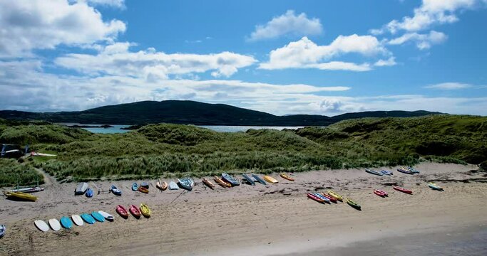 A rising 4K drone shot of Derrynane Caherdaniel beach with  colourful kayaks and Mountains in the backdrop