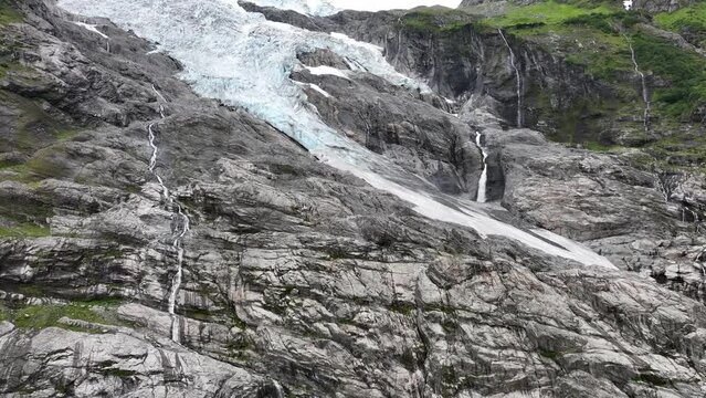 Boyabreen Glacier - The tongue and edge of the Jostedal Glacier in Fjaerland Norway - Upward moving aerial revealing full glacier view with stream of melted glacial water to the right - 60FPS