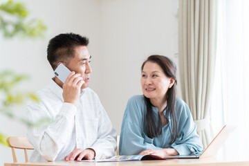 旅行パンフレットを見て予約をするシニア夫婦