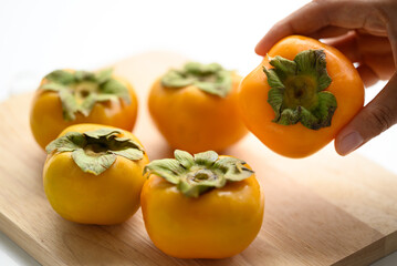 Fresh persimmon fruit with hand in autumn season