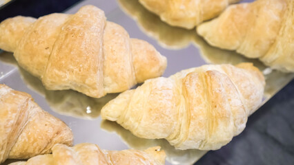 Display window with pastry - butter croissant in showcase. Freshly baked plain croissant sale in the shop and on the market.