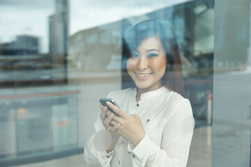 Asian Business woman using a smartphone and looking out window