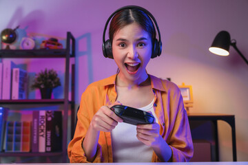 Excited Young Asian woman holding joysticks with playing online game.