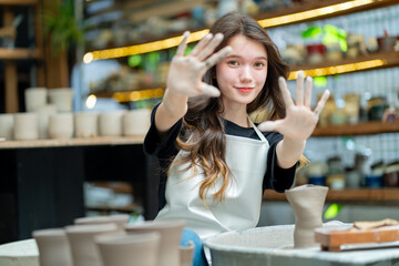 Capturing the artistry in motion, a young woman meticulously scrapes pottery, creating a...