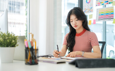 Stylish young woman using graphics tablet and a stylus pen, working new project in home office.