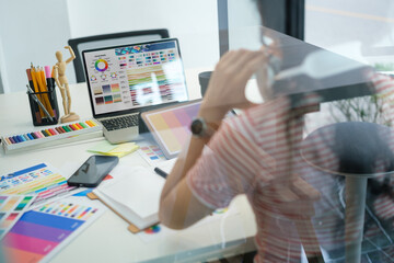 View through glass window of creative woman working in modern office.