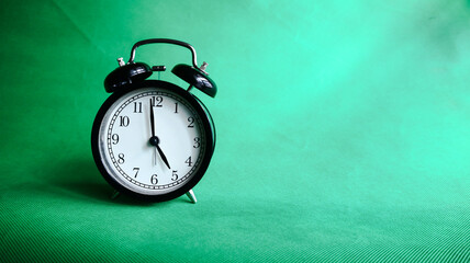5:00 o'clock, alarm clock isolated on green background