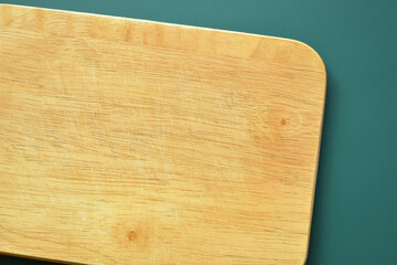 brown wooden cutting board on green background, equipment for cooking in the kitchen