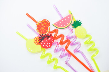 close up colorful fruit drinking staws on white background