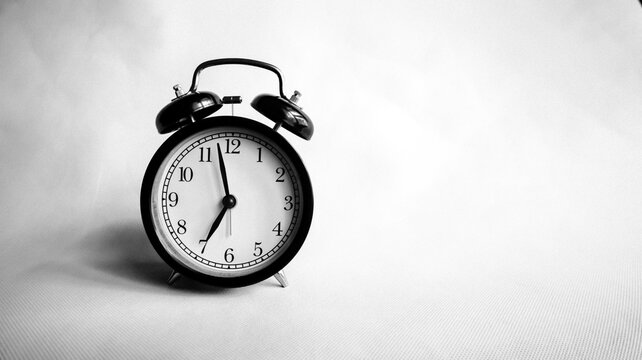 Background photo of an alarm clock showing 7:00 o'clock, black and white concept