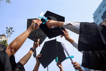 Low angle shot of mortarboards on background of blue sky. Concept of education, friendship and...