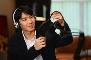 Young man radio host using condenser microphone to recording recording audio for social media...
