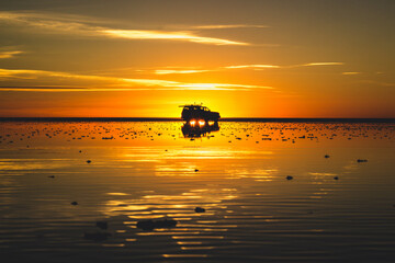 A silhouette of a 4x4 pickup truck reflecting in the water in a golden sunset time in  Salar de...