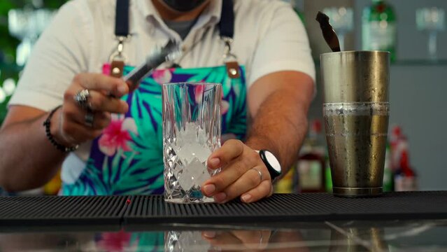latin mexican mixologist prepare exotic cocktail drink at beach restaurant tequila mezcal mojito gin refresher fresh with cucumber garnish serving from shaker