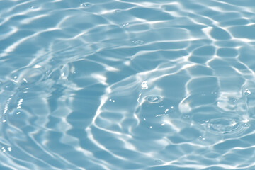 Blue water with ripples on the surface. Defocus blurred transparent blue colored clear calm water surface texture with splashes and bubbles. Water waves with shining pattern texture background.