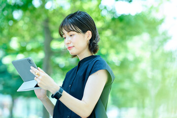 Fototapeta premium 屋外でタブレットPCを操作する若い女性