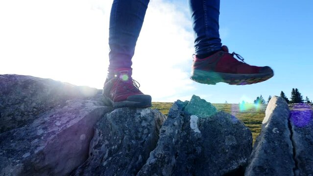 Hiker walking over stone rocks step by step outdoors in alpine nature landscape