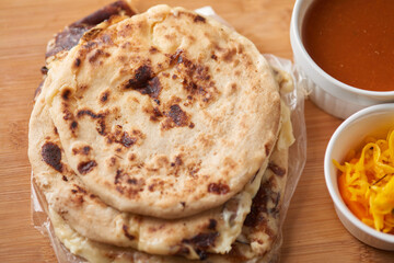 Central America traditional pupusas, a flavorful delight from El Salvador, Honduras, and Nicaragua, served with curtido and sauce on a rustic wooden tray