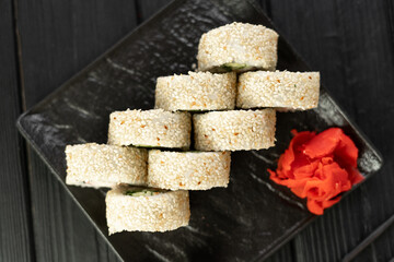 Sushi roll sushi with prawn, avocado, cream cheese and sesame on black background, top view. Sushi menu concept. Japanese food.