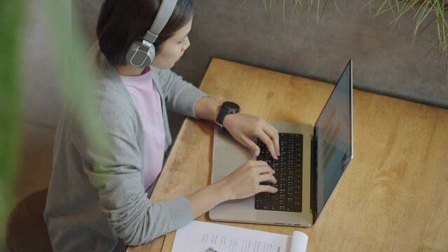 Asian Student female wear headphones learn watching online webinar webcast class looking at laptop,Asian Young Woman studying online at home