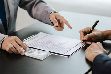 Asian businessmen shaking hands and accepting bribes at table concept of corruption