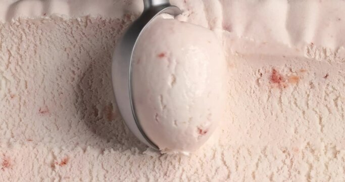 strawberry ice cream scooping out of container by metal spoon