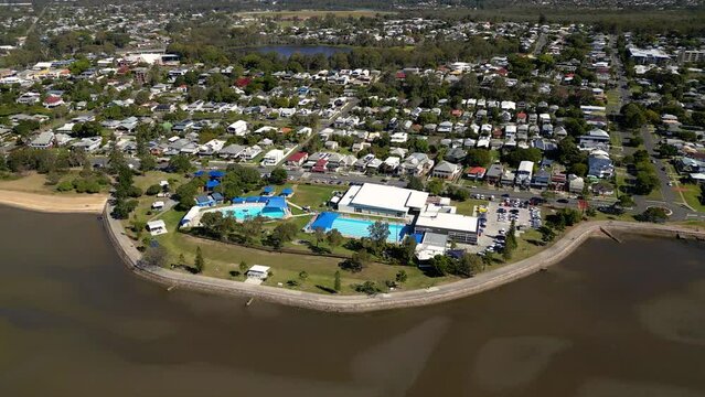 Aerial view of Sandgate pool moving left to right and Brighton waterfront on a sunny day, Brisbane, Queensland, Australia