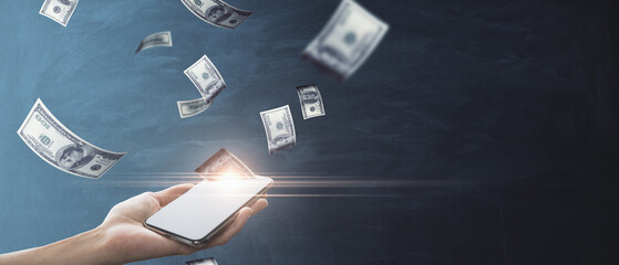 Online earnings concept with woman hand holding cellphone and US dollar banknotes on dark background