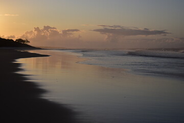 Sepia-toned sunset with distant clouds on a wide sandy beach