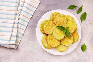 Baked zucchini with cheese, garlic and fresh herbs on a gray background.