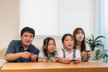 ゲームを楽しむ双子のいる若い家族、仲良しファミリーイメージ