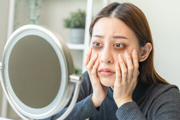 Bored, insomnia asian young woman, girl looking at mirror hand touching under eyes with problem of...