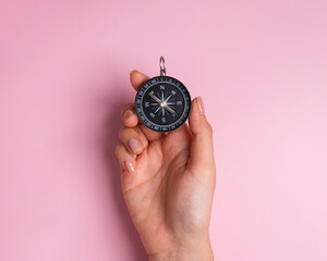Top view of hand holding compass on pink background, Searching direction concept. © Tiwaporn Khemwatchar
