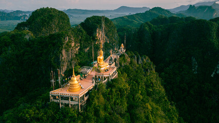 Beautiful aerial drone view of buddha statue on top of the mountain at sunrise, Wat Tham Sua (Seua)...