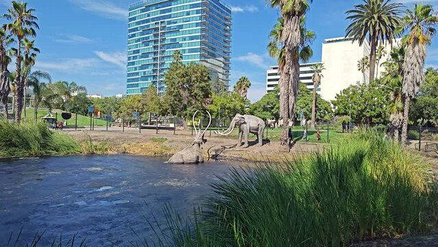 World famous La Brea Tar Pit with statues of wooly mammoths with one trapped in the tar pit, in Los Angeles, California