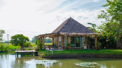 Obraz premium Bamboo hut homestay farm with Green rice paddy fields in Central Thailand Suphanburi region, drone aerial view of green rice fields in Thailand