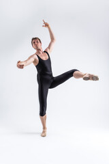 Fototapeta na wymiar Sports Ideas. Athletic Caucasian Ballet Dancer Man Posing in Dancing Stretching Pose With Hands Lifted Up in While Standing on Feet in Black Tights On White.