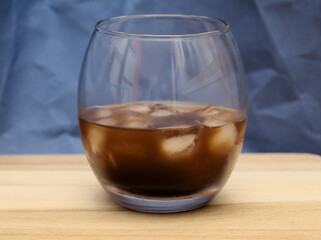 cold coffee drink with ice cubes in it served in a round glass